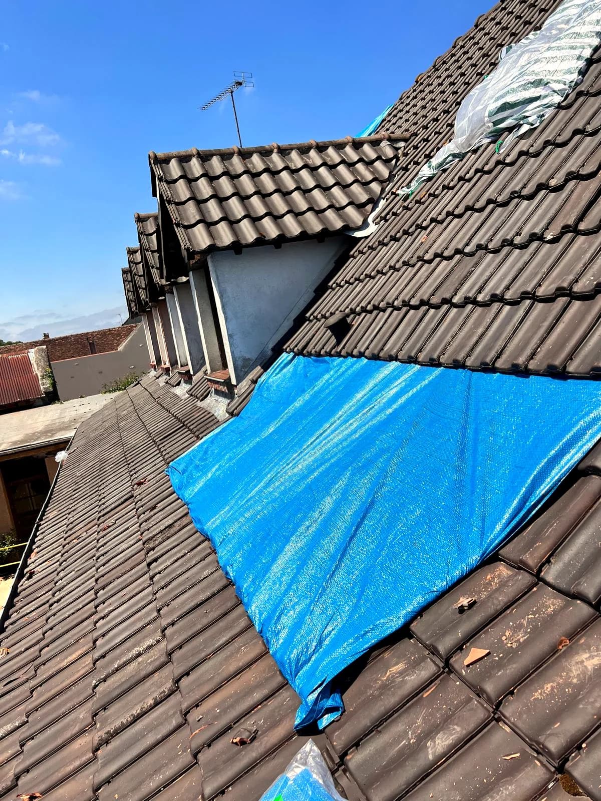 Une bâche bleue tendue sur une toiture pour arrêter une infiltration