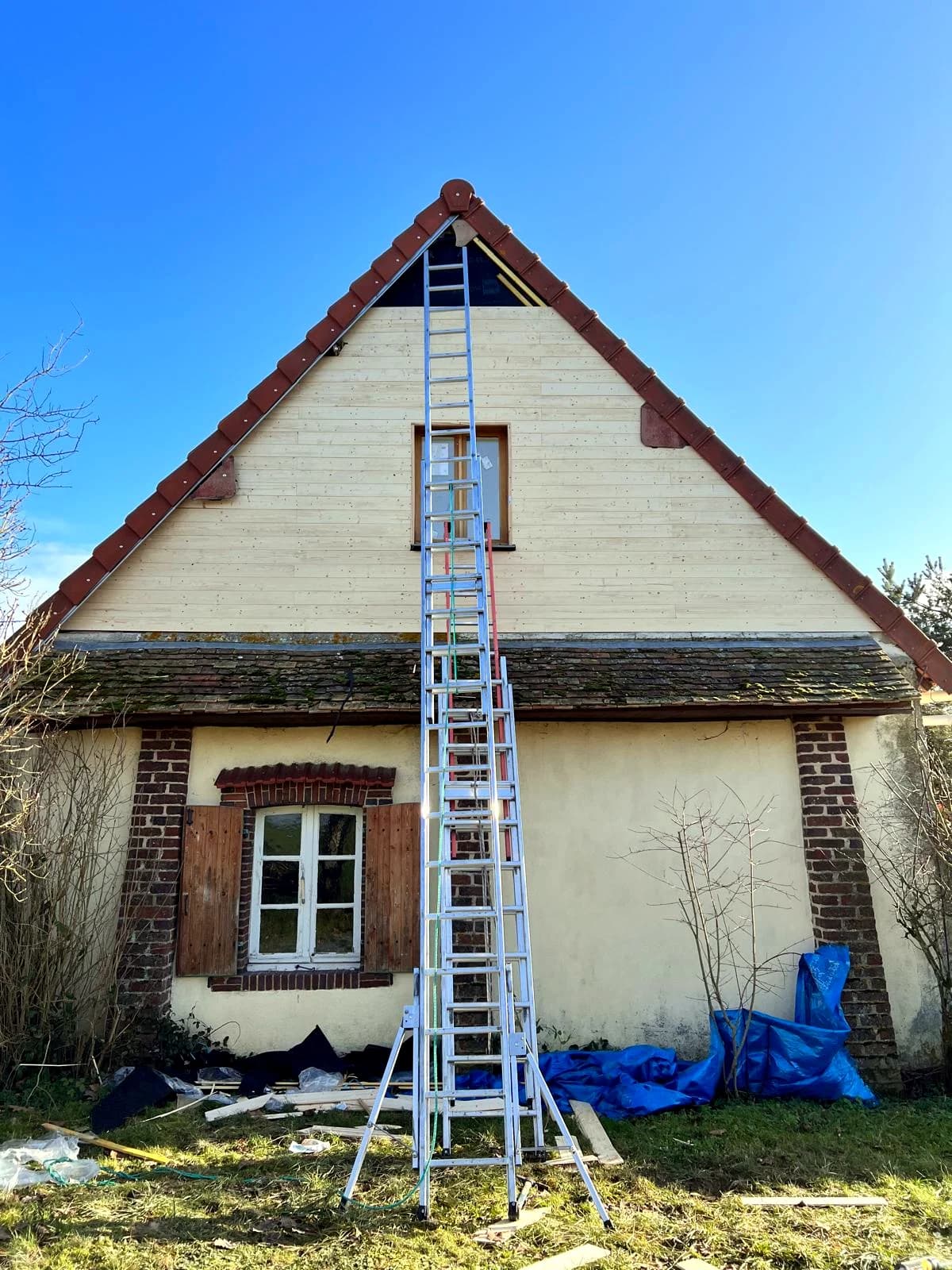 Un pignon en cours de rénovation avec une échelle appuyée contre la façade